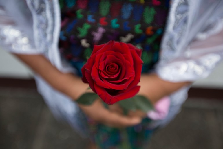 A woman holds a rose in her hands