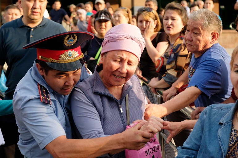 Kazakh police officer detains a woman protester during a rally