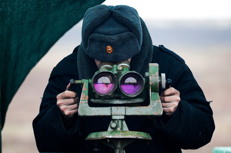 A Russian serviceman looks through a binocular as he takes part in military drills in in southern Russia