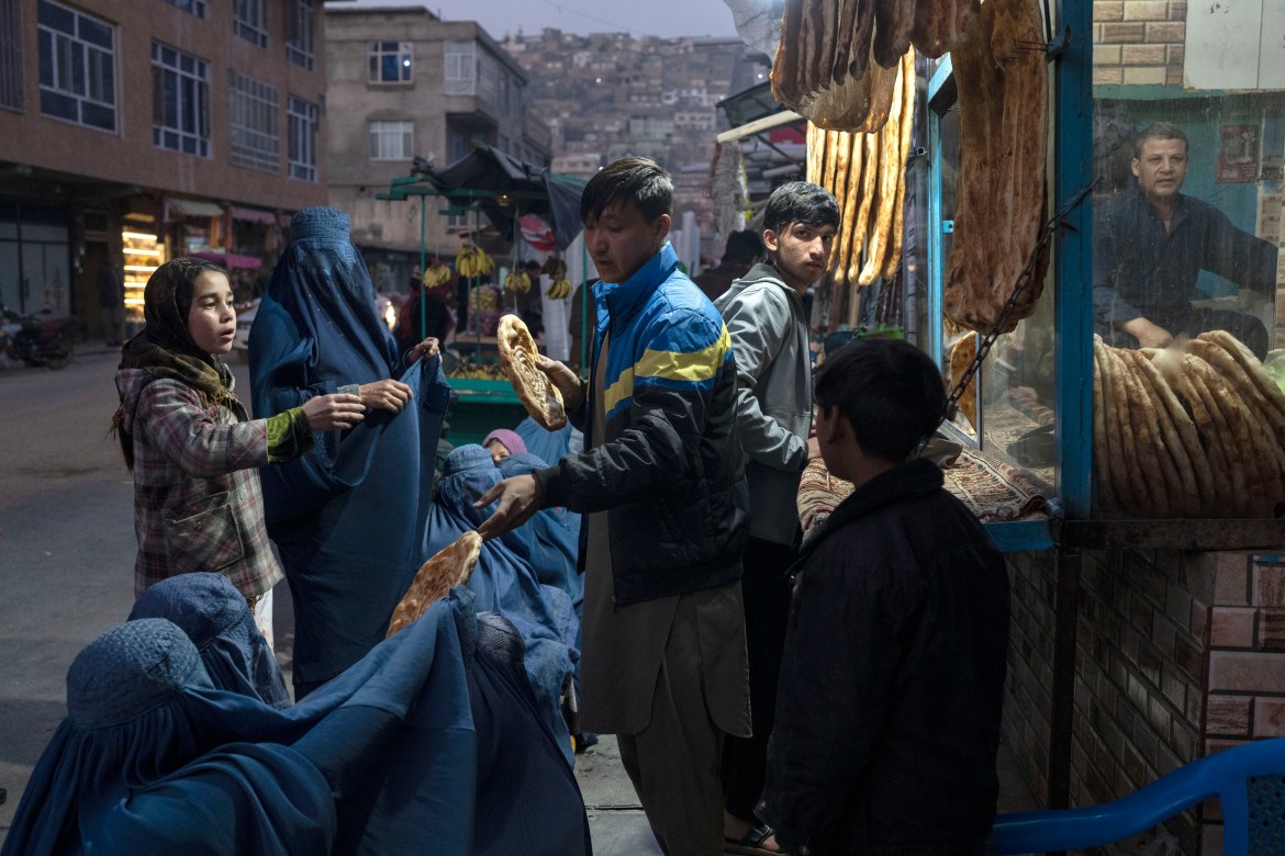 A man disributes bread to Afghan women outside a bakery in Kabul