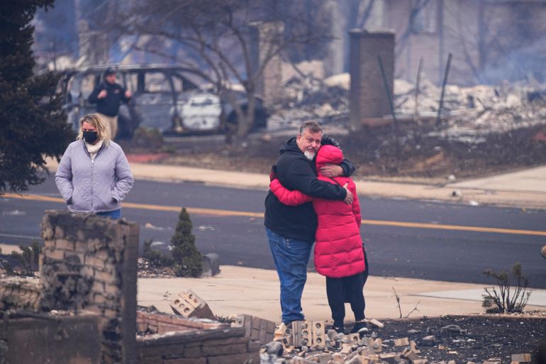 A man hugs his neighbor after finding their homes destroyed, Friday, Dec. 31, 2021, in Louisville, Colorado, after wildfires swept through the day before