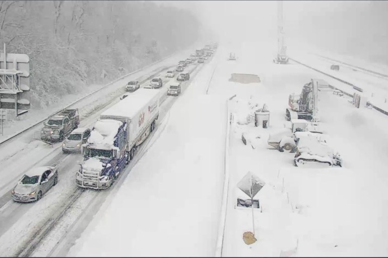 cars and trucks along I-95 at a standstill on snowy roadway