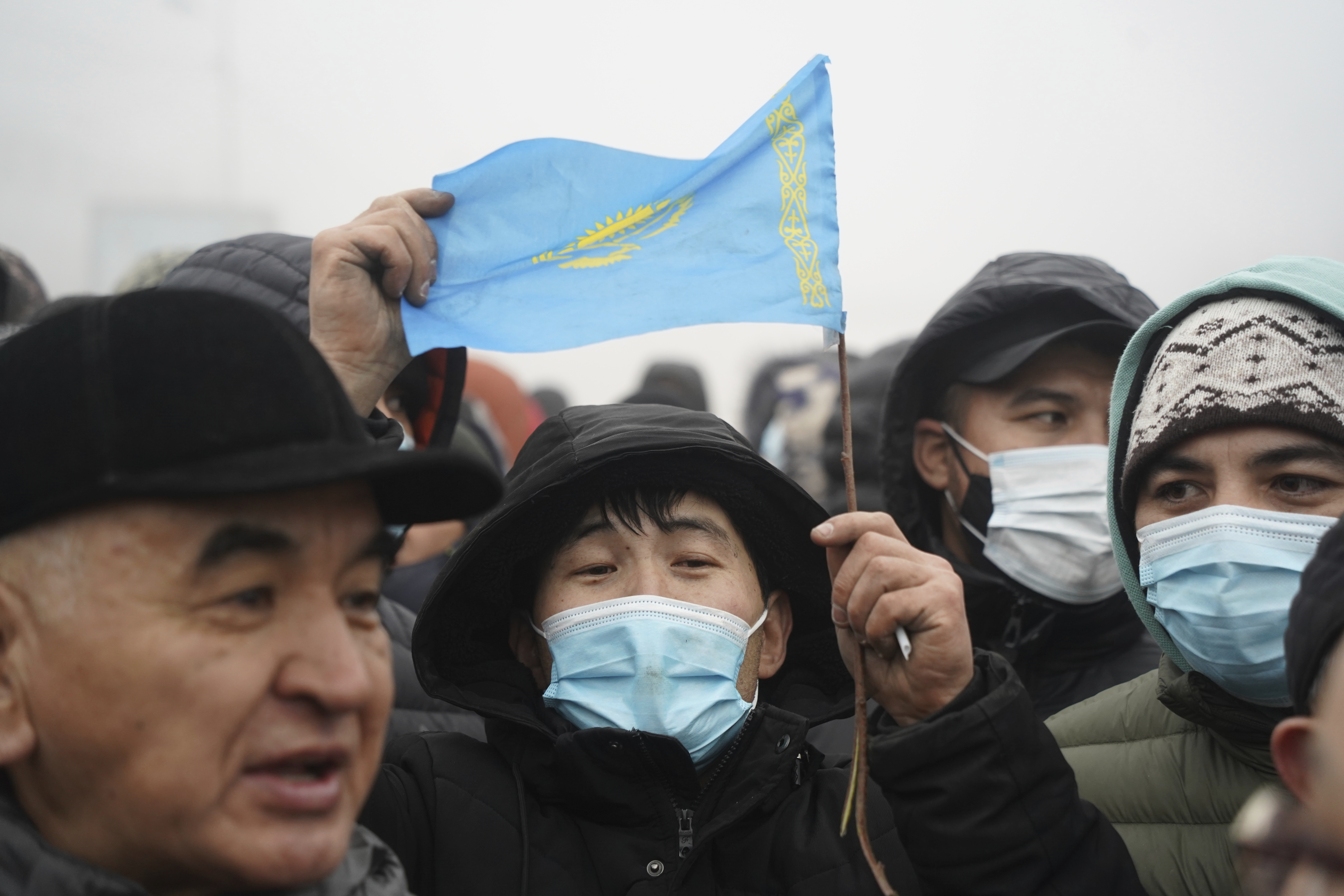 Um homem do Cazaquistão segura uma bandeira do Cazaquistão em meio a uma multidão de manifestantes
