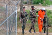A prisoner is led by military police to be interrogated by military officials at Camp X-Ray at the US Naval Base at Guantanamo Bay, Cuba on February 6, 2002 [File: AP/Lynne Sladky]