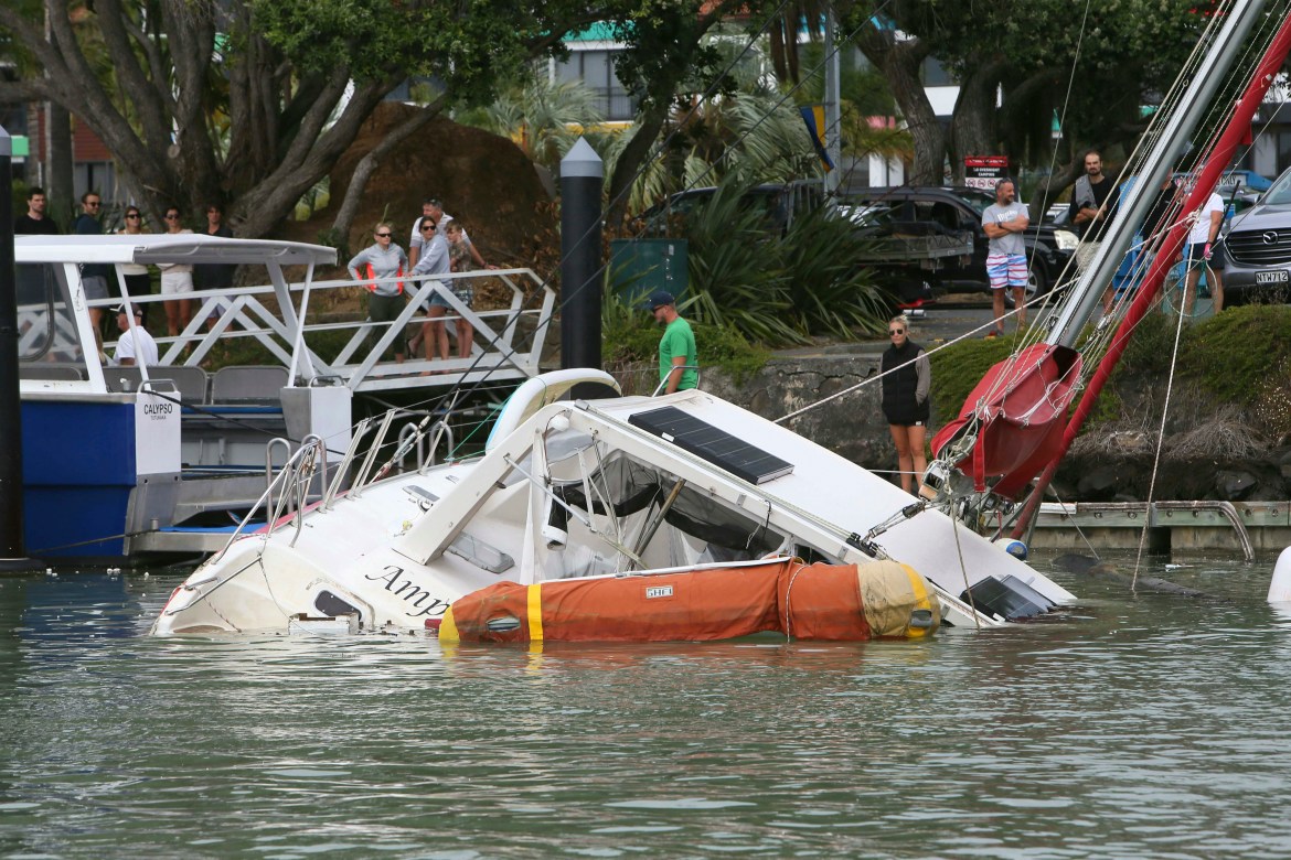 People look at a damaged boat in a marina at Tutukaka, New Zealand