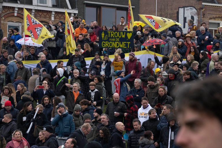 A sign, center top, reads "Please Remain Faithful to the Constitution" as thousands of people protested against the Dutch government's coronavirus lockdown measures in Amsterdam, Netherlands