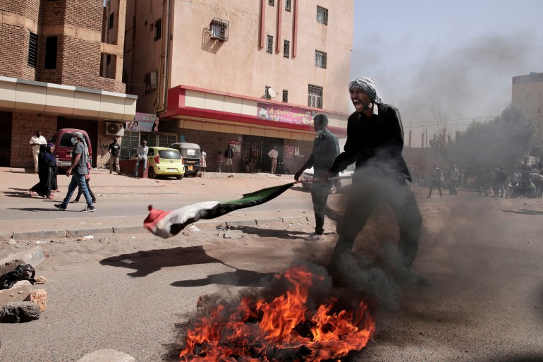 A demonstrator is seen next to fire burning on the ground in Khartoum, Sudan