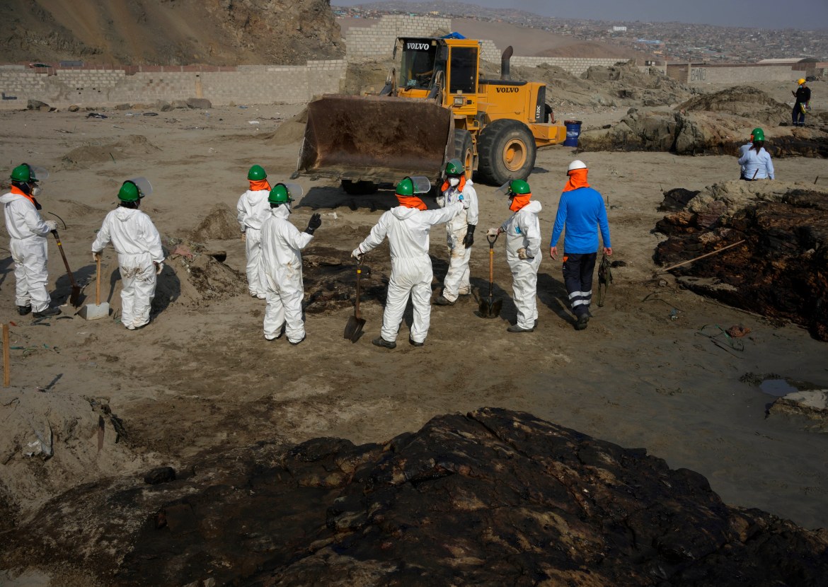 Workers clean up an oil spill caused by abnormal waves in Ventanilla, Peru