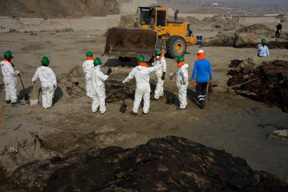 Workers clean up an oil spill caused by abnormal waves in Ventanilla, Peru