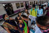 A health worker collects a swab sample from a traveller at a train station to test for COVID-19 before allowing her to enter Mumbai [Rajanish Kakade/AP]
