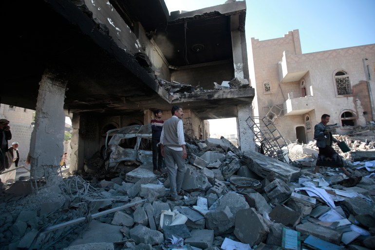 People inspect the wreckage of buildings damaged by Saudi-led coalition airstrikes in Sanaa