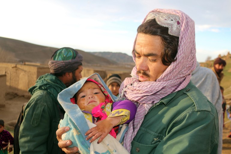 An Afghan man hold his injured daughter after his home was damaged by earthquake