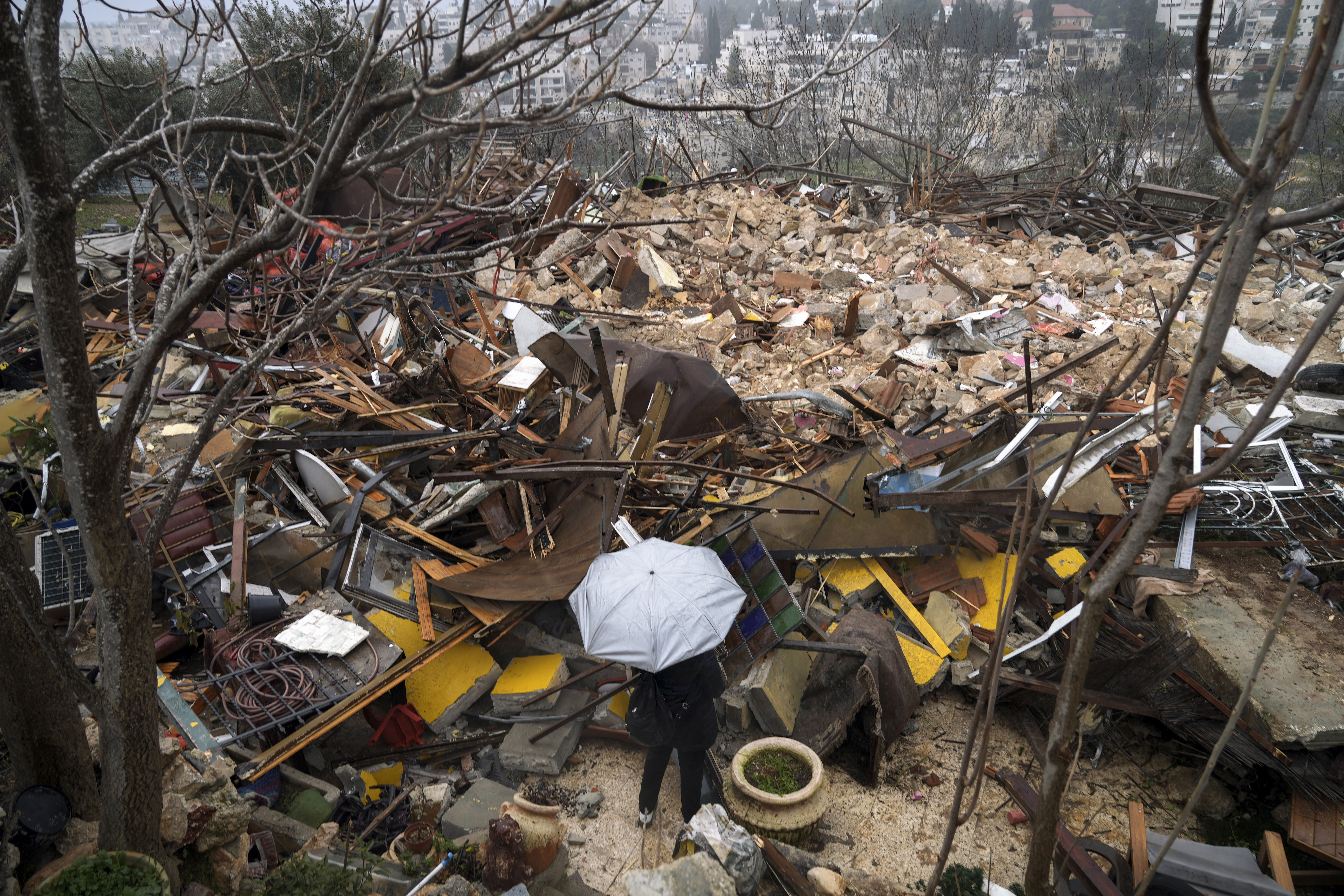 Una donna osserva le rovine di una casa palestinese demolita dal comune di Gerusalemme