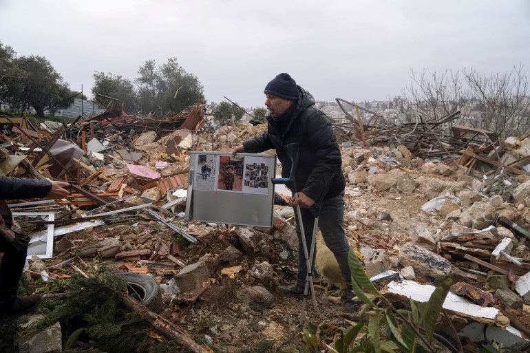 A Palestinian man carries family photos at the ruins of a house demolished by the Jerusalem municipality