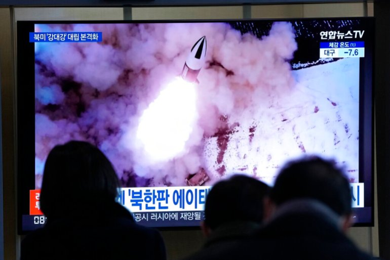 İnsanlar, Güney Kore'nin Seul kentindeki Seul Tren İstasyonu'ndaki bir haber programı sırasında Kuzey Kore'nin füze fırlatmasının dosya görüntüsünü gösteren bir TV izliyor.