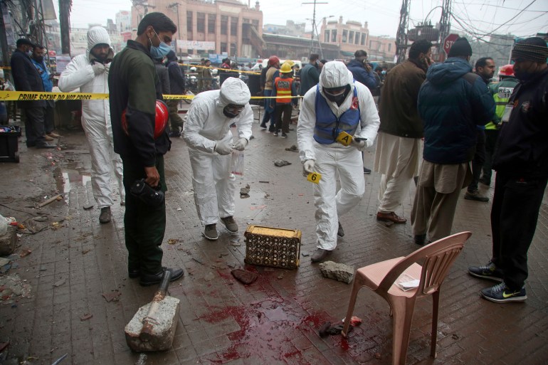 Investigators gather evidence as they examine the site of a bomb explosion, in Lahore, Pakistan, Thursday, Jan. 20, 2022. Police said the powerful bomb exploded in a crowded bazar in Pakistan's second largest city of Lahore, killing several people and wounding dozens of others. (AP Photo/K.M. Chaudary)