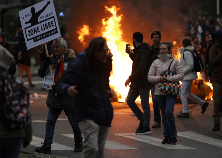 protesters cross the road near a burning fire