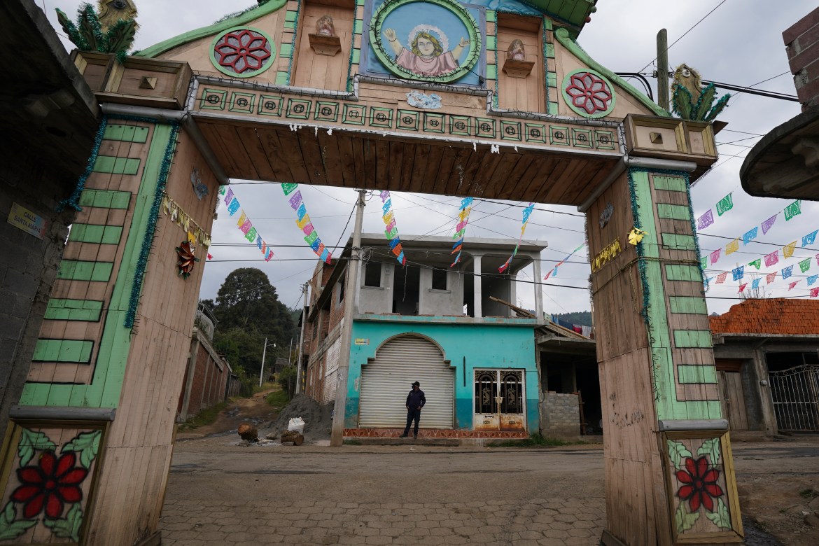 A community police officer stands guard at the main gate to the Purepecha Indigenous community of Comachuen