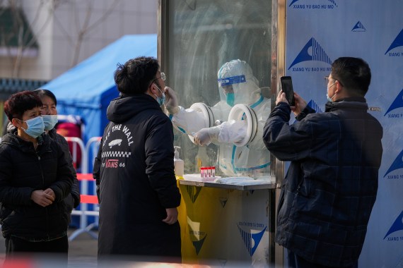 A man uses a smartphone to record residents getting a throat swab at a mass coronavirus test site in Xichen District in Beijing, Tuesday, Jan. 25, 2022. Hong Kong has already suspended many overseas flights and requires arrivals be quarantined, similar to mainland China's "zero-tolerance" approach to the virus that has placed millions under lockdowns and mandates mask wearing, rigorous case tracing and mass testing.