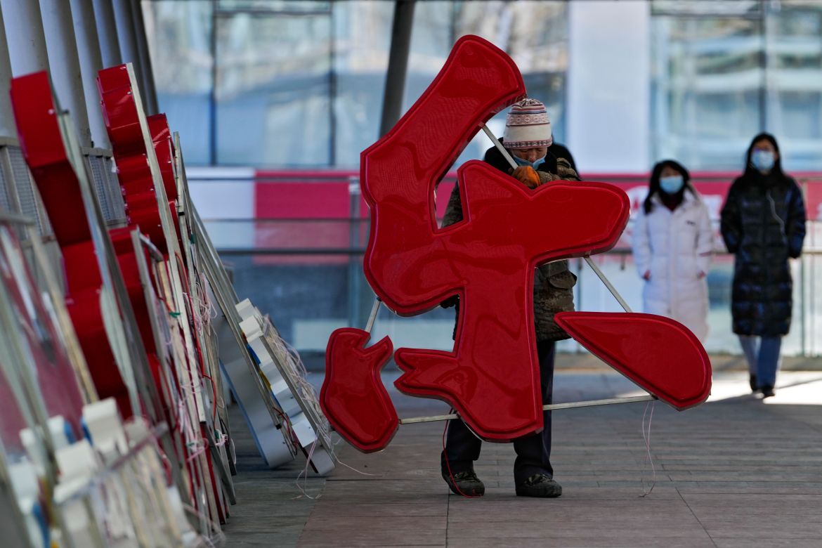 A worker wearing a face mask to help protect from the coronavirus carries characters reading "Happiness" for an installation for the upcoming Chinese Lunar New Year on a pedestrian bridge in Beijing, Tuesday, Jan. 25, 2022. (AP Photo/Andy Wong)