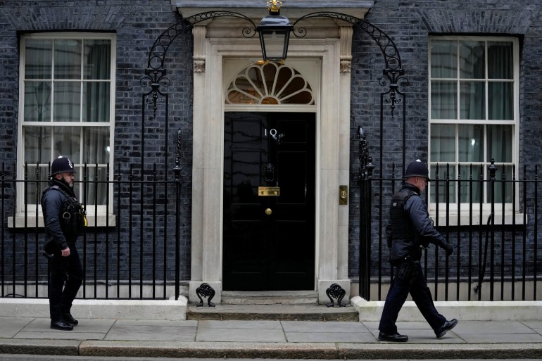 Two metropolitan police officers walk past 10 Downing Street in London