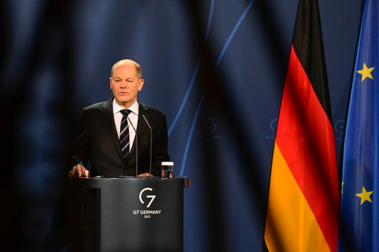German Chancellor Olaf Scholz speaks during a media conference with the German flag in the background