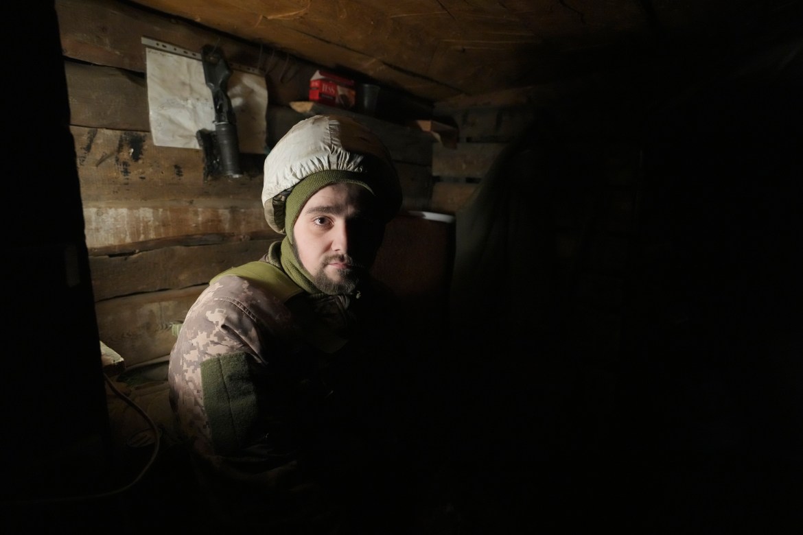 A Ukrainian serviceman looks at a photographer while resting in a shelter on the front line in the Luhansk region, eastern Ukraine, Friday, Jan. 28, 2022.