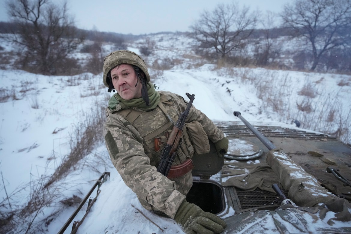 A Ukrainian serviceman looks back from atop an armored personnel carrier driving near a front line position in the Luhansk area, eastern Ukraine