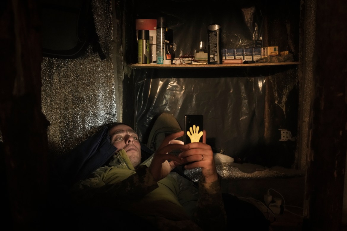 A Ukrainian serviceman lies in bed looking at a mobile phone at a front line position in the Luhansk area, eastern Ukraine, Friday, Jan. 28, 2022.