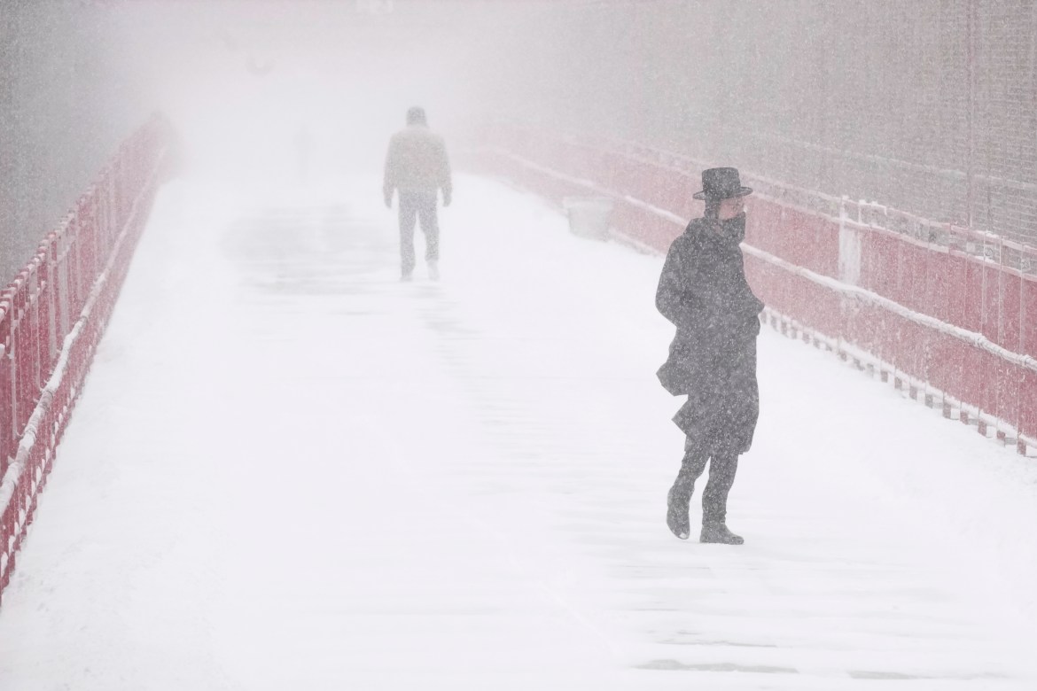 People make their way over the Williamsburg bridge during a snow storm, Saturday, Jan. 29, 2022, in New York