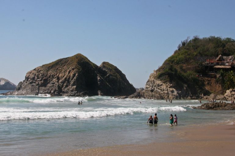Visitors bathe in the surf along the beach in Zipolite, Mexico.