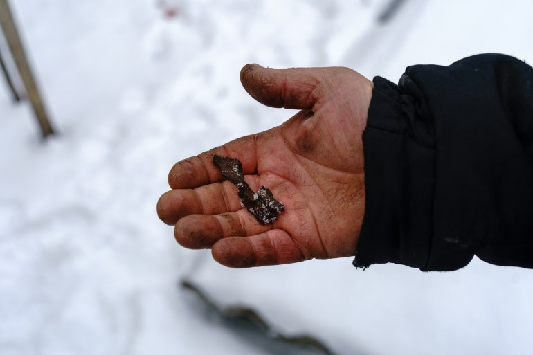 Andriy Dmytryuchenko, 45, showing a shrapnel piece from his old house's garden. Nevelske