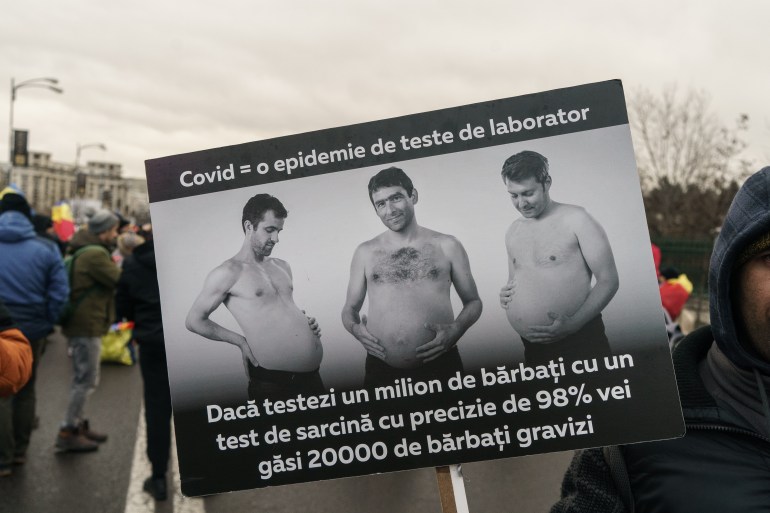متظاهر في بوخارست برومانيا يحمل لافتة تقول "كوفيد = وباء من الاختبارات المعملية"