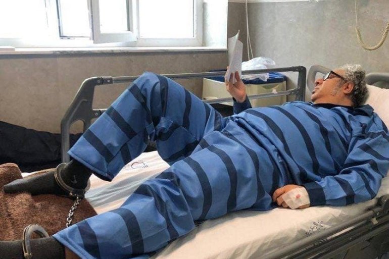 Iranian writer Baktash Abtin reads while shackled to a hospital bed after being admitted for contracting COVID