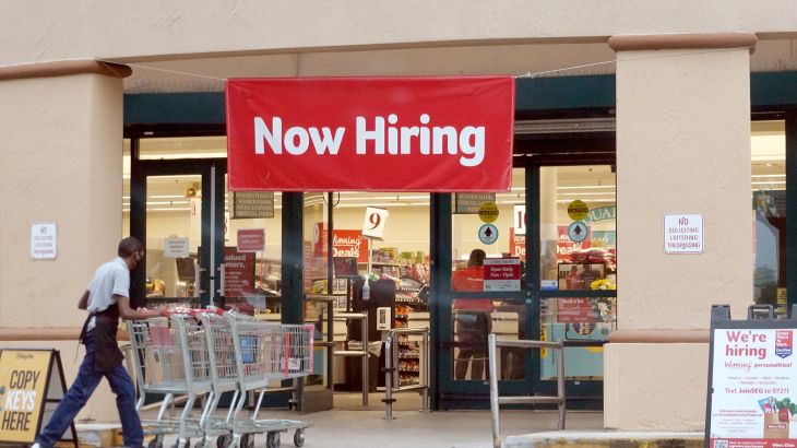 "Now hiring" sign in shop window