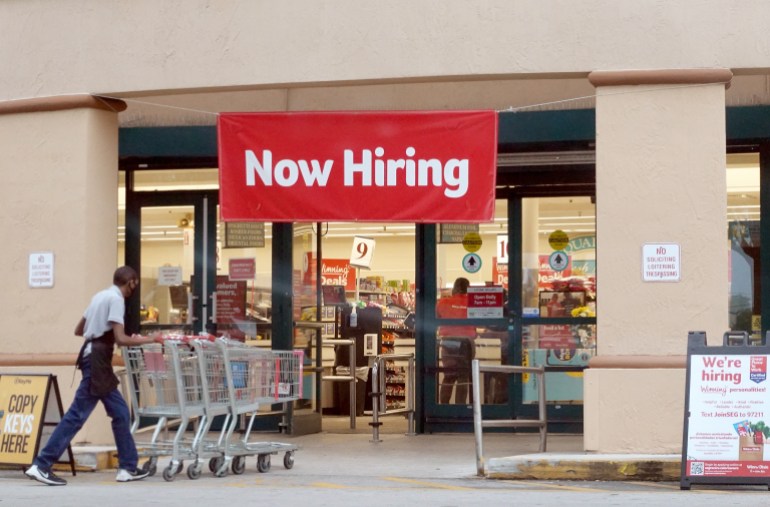 "Now hiring" sign in shop window