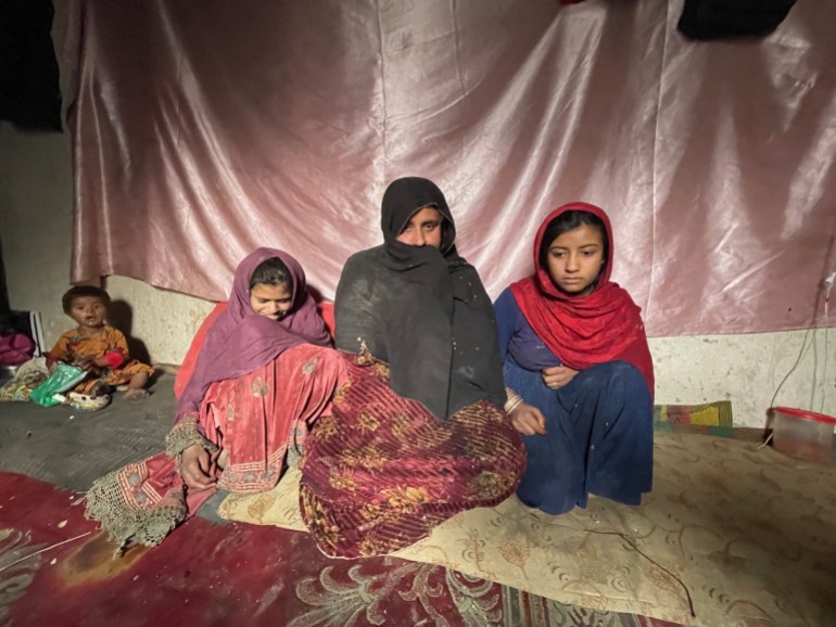 Mulher afegã chamada Zaigul está sentada no chão de sua casa com seus filhos.