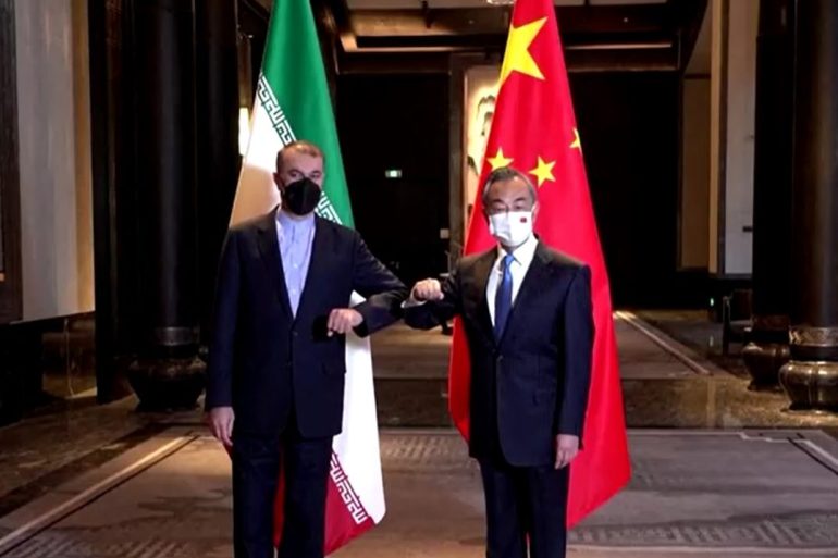 Chinese Foreign Minister Wang Yi stands with his Iranian counterpart Hossein Amirabdollahian (left) in front of their countries' flags during a meeting in Wuxi, in Jiangsu province.
