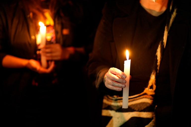 People hold candles during a protest against the murder of journalists
