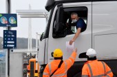 A truck driver shows documentation to officials as he arrives at the Eurotunnel at Folkestone, UK [Toby Melville/Reuters]