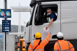 A lorry driver shows documentation to officials for both customs clearance and COVID-19.
