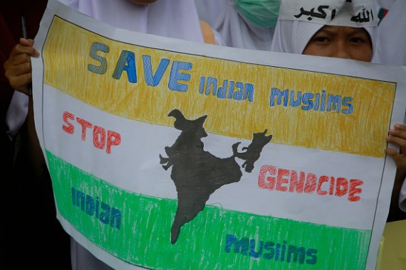 A woman holds a poster alleging the genocide of Muslims in India.