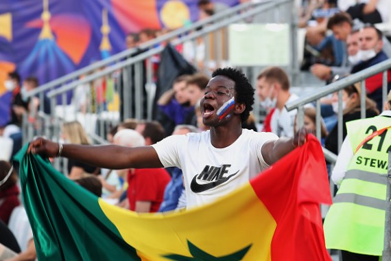 A Senegal fan waves a flag during a football match. Senegal, among the tournament favourites, has postponed travel plans after suspected positive cases.