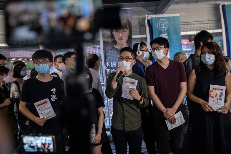Pro-democracy activists and Demosisto members Joshua Wong (L), Jannelle Leung (2-L), Nathan Law (C), Sunny Cheung (2-R), and Gwyneth Ho (R), all wearing face masks, distribute pamphlets against China's controversial national security law for Hong Kong