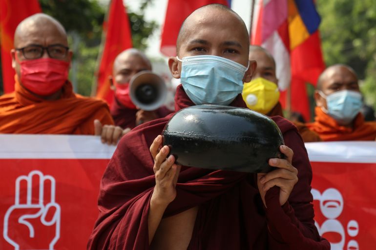 A Buddhist monk in saffron robes holds an alms bowl as he takes part in a protest in support of Myanmar's anti-coup movement