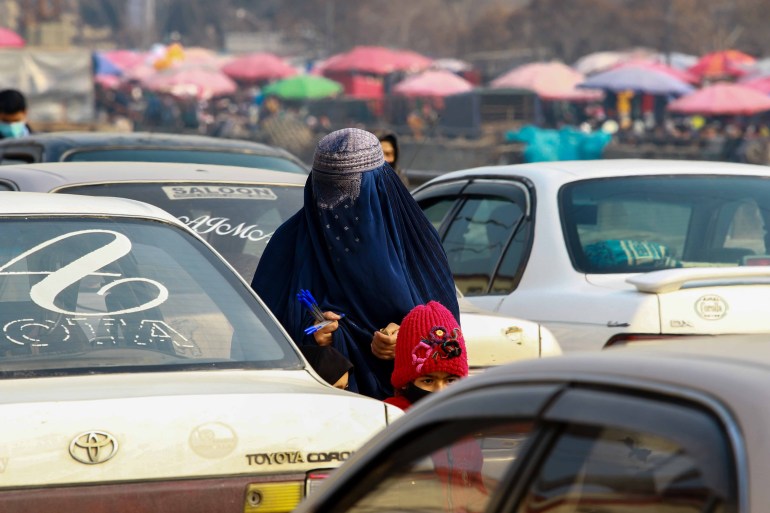 A burqa-clad Afghan woman sells stationary on a road in Kabul, Afghanistan, 27 December 2021. 