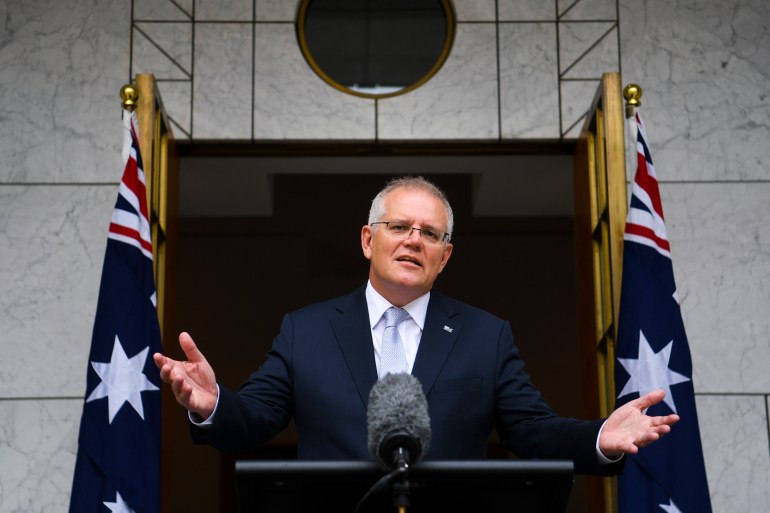 اسکات موریسون، نخست وزیر استرالیا هنگام صحبت با خبرنگاران در کانبرا، دستان خود را بالا می برد