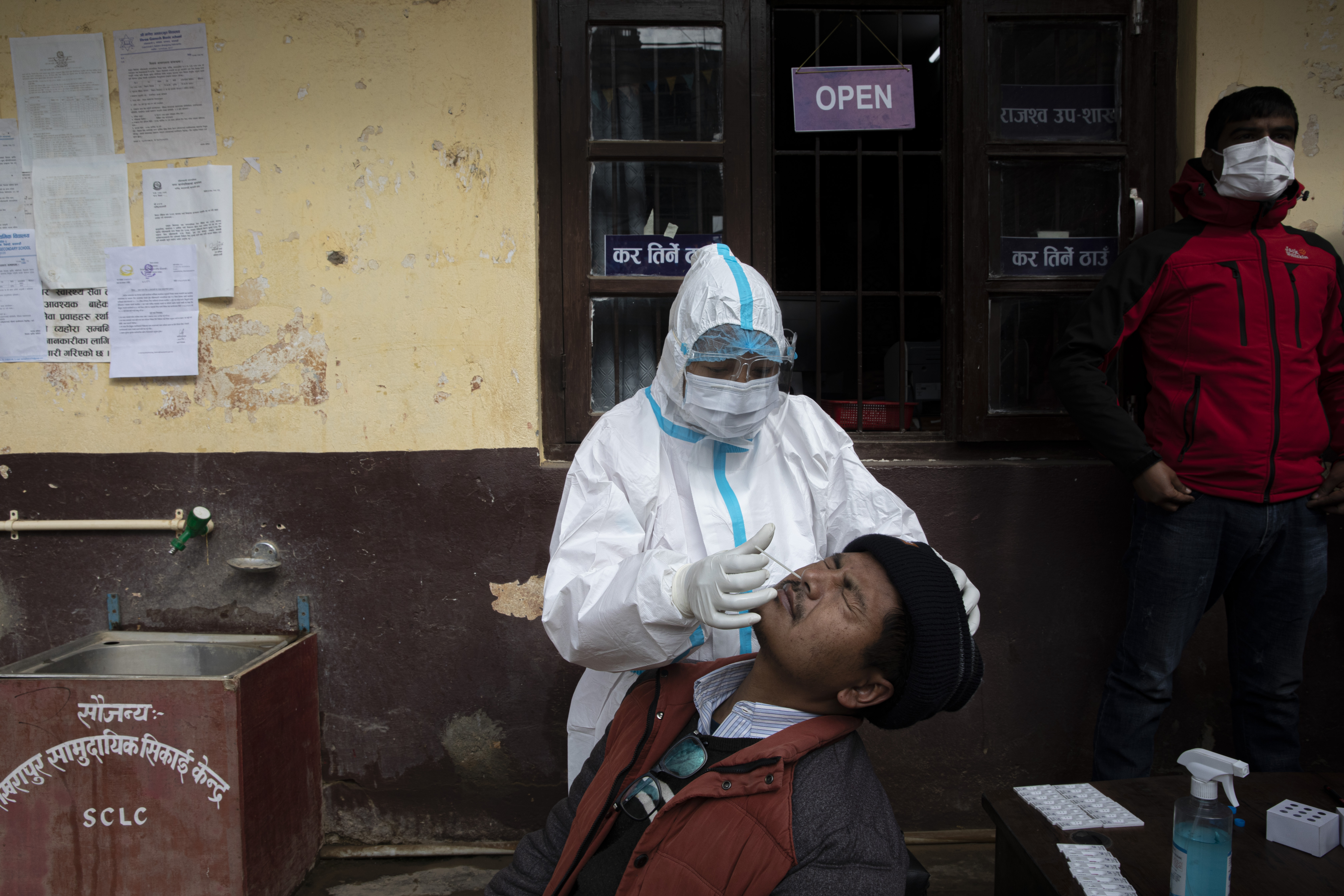 Un uomo nepalese reagisce mentre l'operatore sanitario raccoglie il campione di tampone