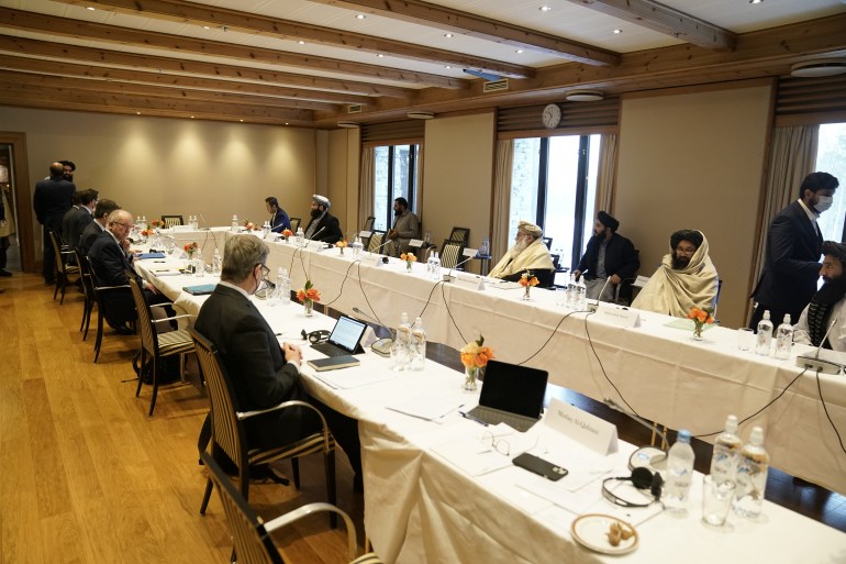 International special representatives and representatives from the Taliban sit at a negotiation table