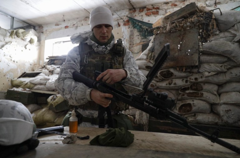 Soldado ucraniano limpa uma arma nas posições em uma linha de frente perto da aldeia Avdiivka
